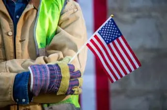 Worker holding an American flag - Economic benefits of immigration