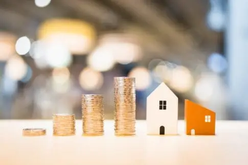 Stacks of coins next to houses represent high mortgage rates