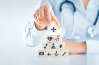 A medical professional stacks blocks that symbolize parts of the health care system