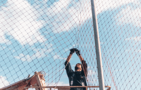 A worker strengthens a safety net on a construction site, reflecting how government safety nets have evolved since 1970, reducing poverty and the share of Americans who don't have health insurance.