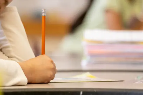 Student holds pencil while filling out worksheet on desk