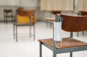 Medical face mask hanging on classroom chair