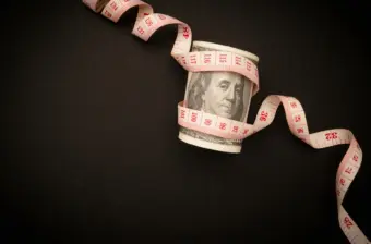Tape measure wrapped around a US dollar banknote