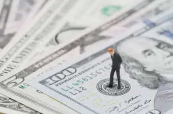 Miniature businessman standing on money