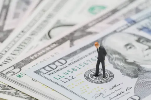 Miniature businessman standing on money