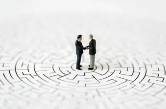 Miniature business people shake hands