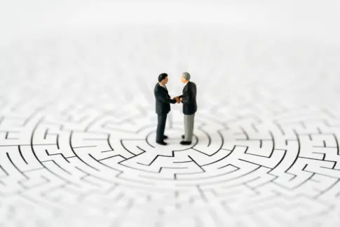 Miniature business people shake hands