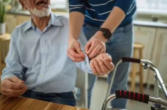 Careworker assisting older man at home with a blood pressure monitor