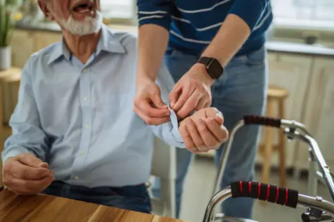 Careworker assisting older man at home with a blood pressure monitor