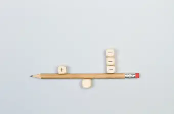 Minus and plus signs wooden cubes with a pencil in balance
