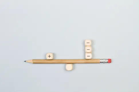 Minus and plus signs wooden cubes with a pencil in balance