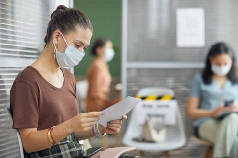 Person wearing a mask and holding a unemployment insurance application