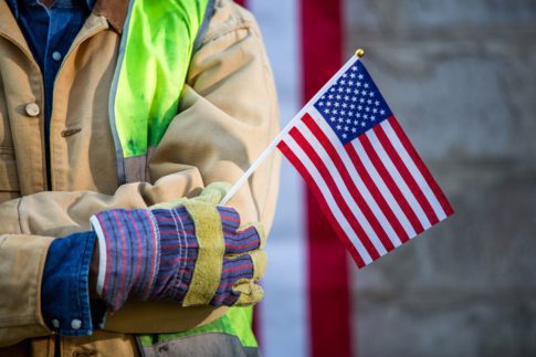 Worker holding an American flag - Economic benefits of immigration