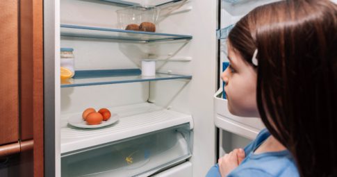 A child looks in an almost empty fridge