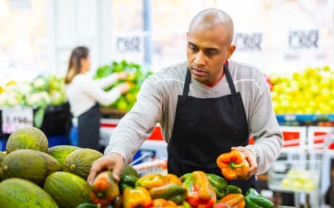 A worker at a grocery store arranges food