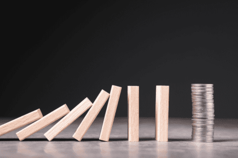 Blocks fall toward a stack of coins, representing unexpected events that could cause financial hardship for SNAP recipients